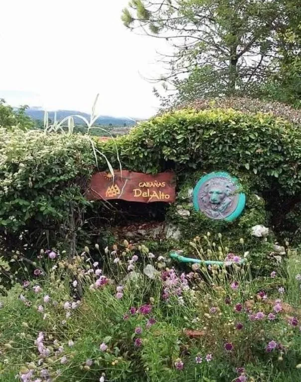 Cartel de entrada de Cabañas Del Alto entre flores