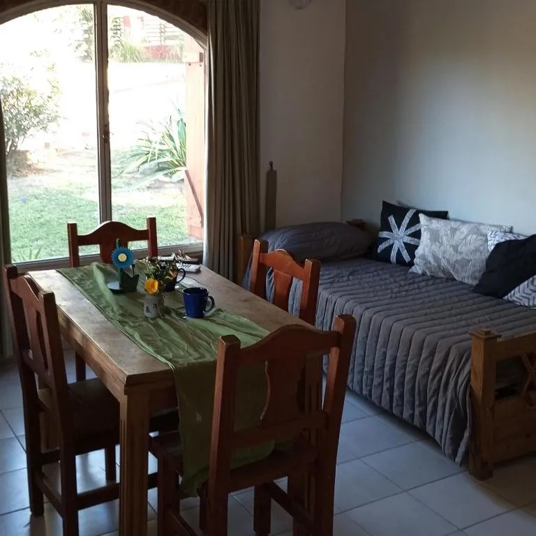 Living comedor con mesa de madera y cama de una plaza junto a la ventana